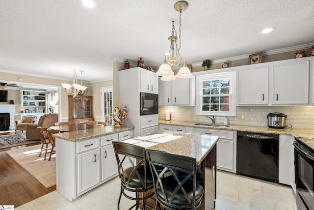 kitchen featuring pendant lighting, a center island, white cabinetry, and black appliances