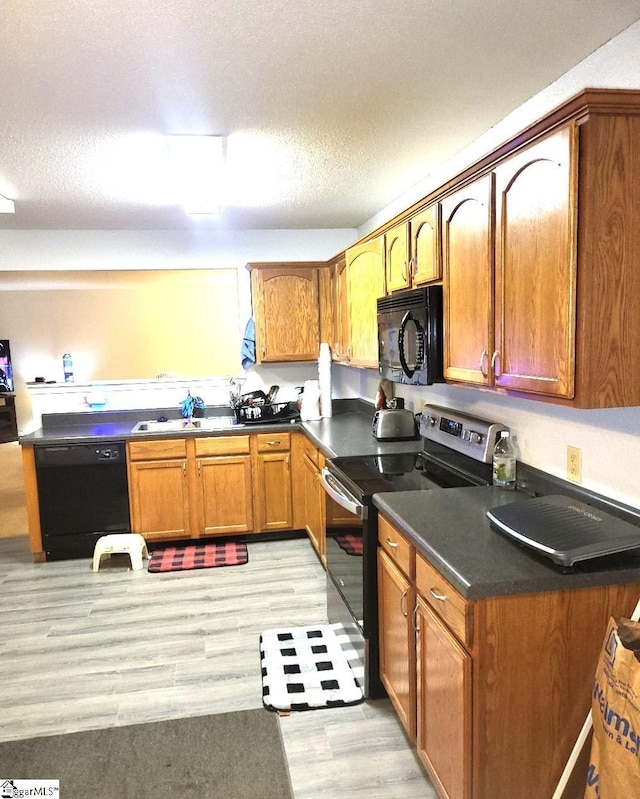 kitchen featuring black appliances, sink, a textured ceiling, and light hardwood / wood-style flooring