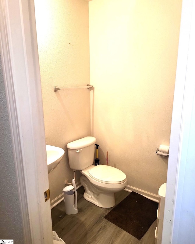 bathroom featuring wood-type flooring and toilet