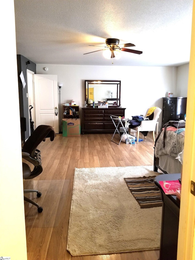 bedroom with ceiling fan, wood-type flooring, and a textured ceiling