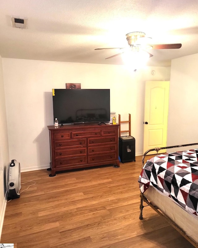 bedroom featuring ceiling fan, light wood-type flooring, and a textured ceiling