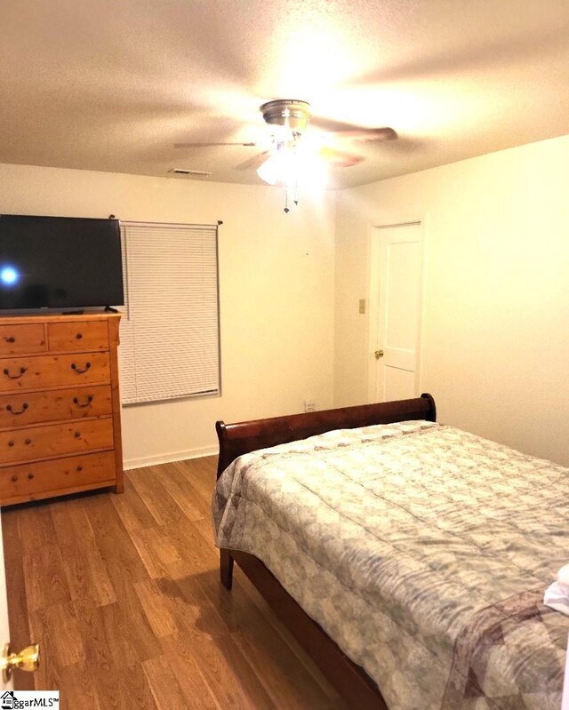 bedroom featuring wood-type flooring, a textured ceiling, and ceiling fan