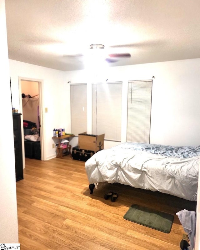 bedroom featuring a textured ceiling, light wood-type flooring, and ceiling fan