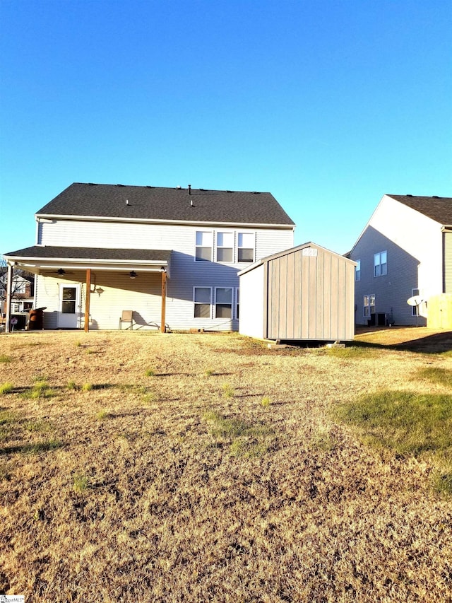 rear view of property featuring a yard and a shed