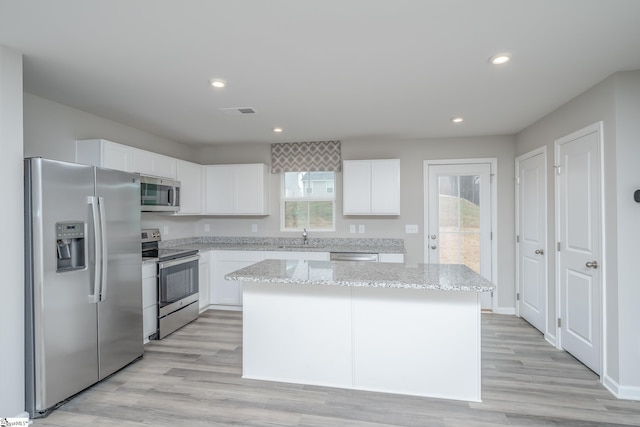 kitchen with stainless steel appliances, a kitchen island, white cabinetry, and a healthy amount of sunlight