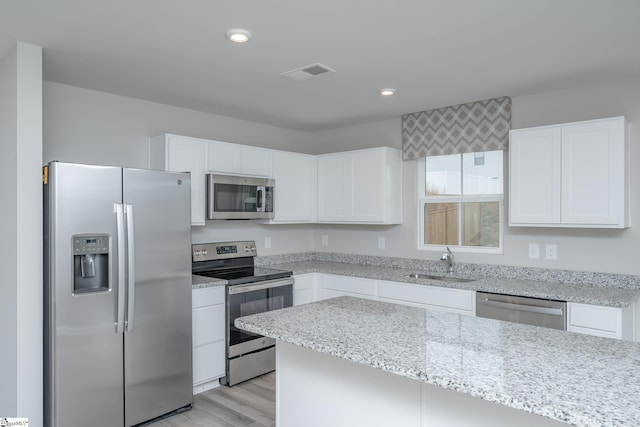 kitchen with white cabinets, light hardwood / wood-style floors, sink, and appliances with stainless steel finishes