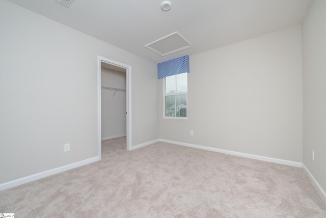 unfurnished bedroom with light colored carpet, a walk in closet, and a closet