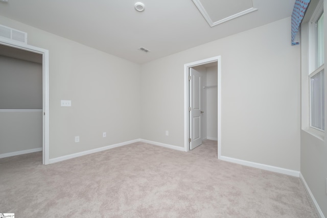 unfurnished bedroom featuring a spacious closet and light carpet