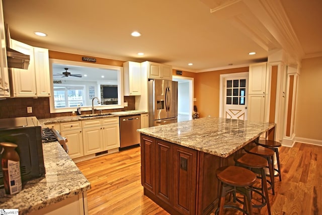 kitchen featuring appliances with stainless steel finishes, white cabinetry, a kitchen island, and sink