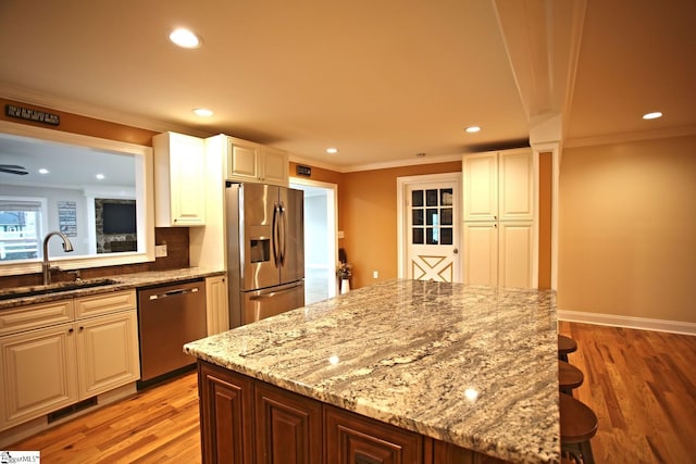 kitchen with a kitchen bar, stainless steel appliances, white cabinetry, and sink