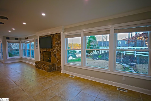 unfurnished living room with plenty of natural light, crown molding, and a fireplace