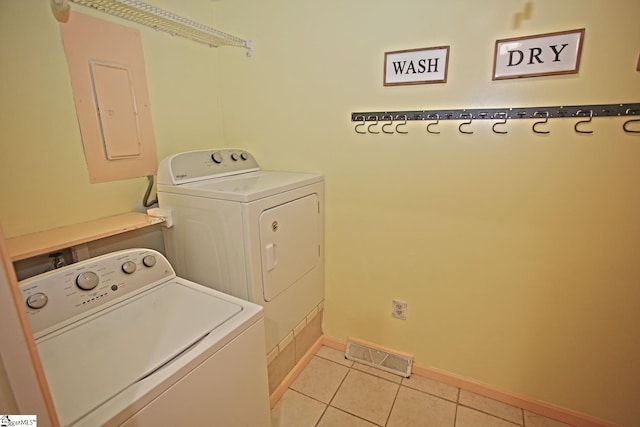 laundry area with independent washer and dryer, electric panel, and light tile patterned floors