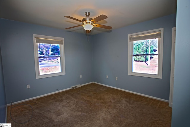 spare room featuring dark carpet and ceiling fan