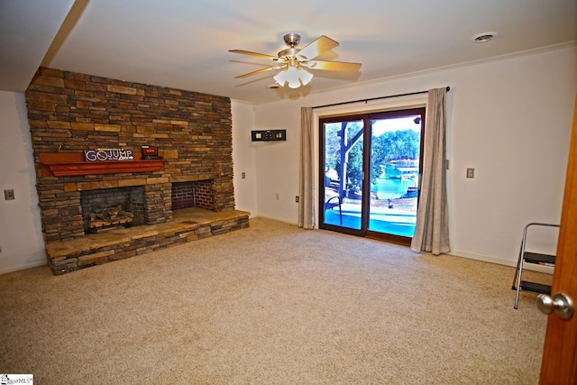 unfurnished living room featuring carpet, ceiling fan, a stone fireplace, and ornamental molding