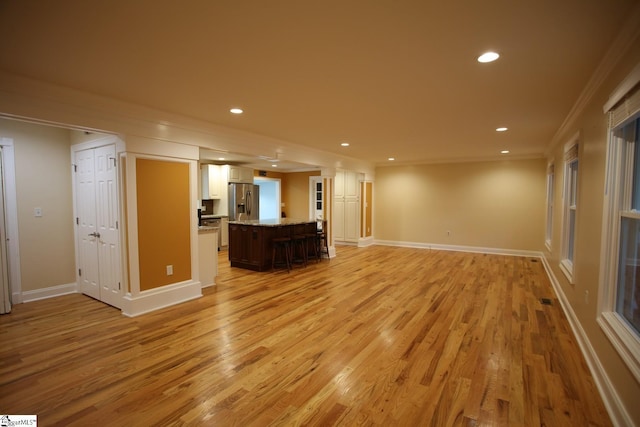 unfurnished living room featuring crown molding and light hardwood / wood-style flooring