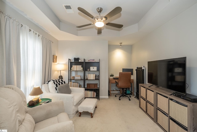 carpeted living room with a raised ceiling, ceiling fan, and plenty of natural light