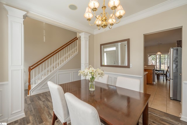 dining room with a notable chandelier, dark hardwood / wood-style floors, crown molding, and decorative columns