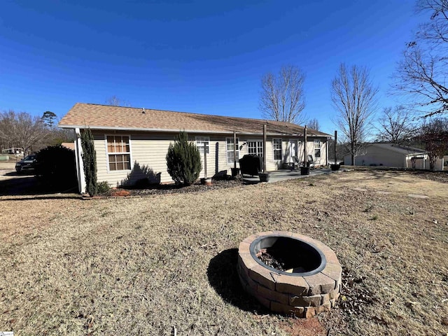 rear view of property featuring a fire pit and a patio