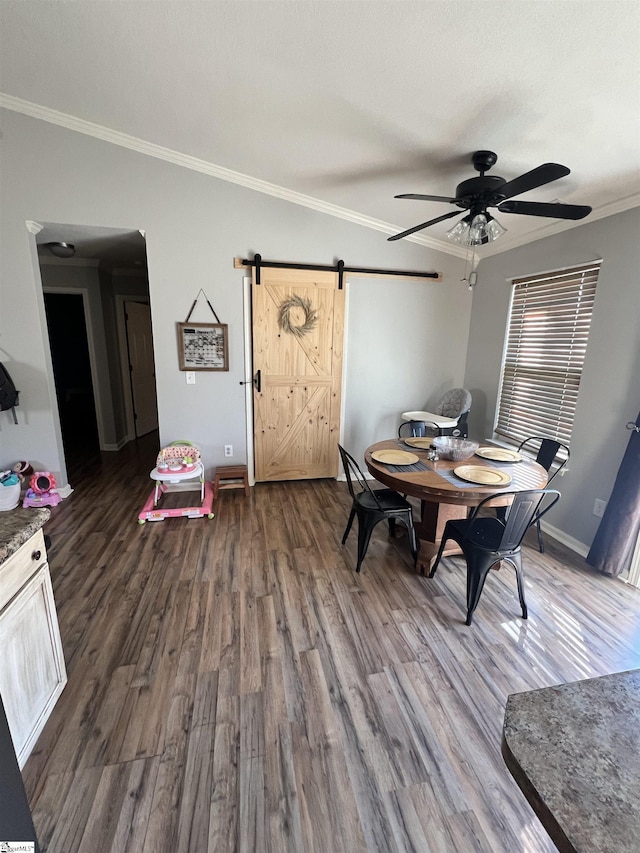 dining area featuring dark hardwood / wood-style flooring, a barn door, ceiling fan, and ornamental molding