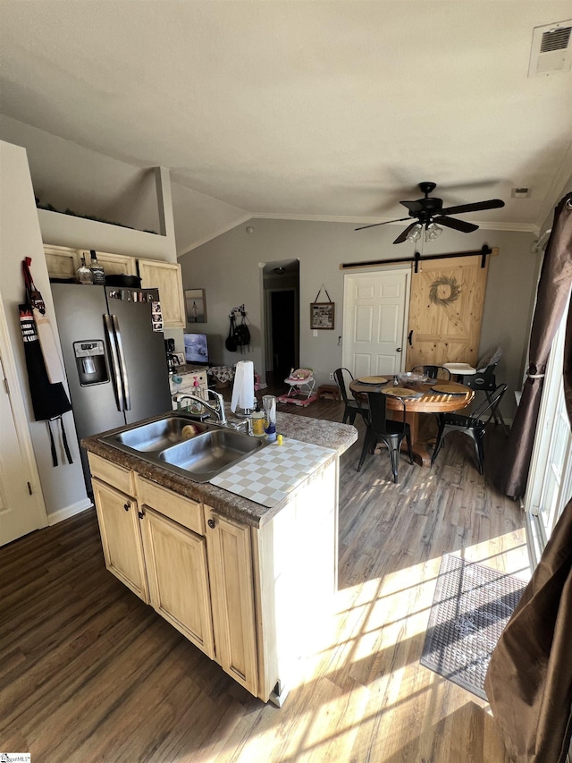 kitchen featuring sink, a barn door, stainless steel refrigerator with ice dispenser, vaulted ceiling, and light brown cabinetry