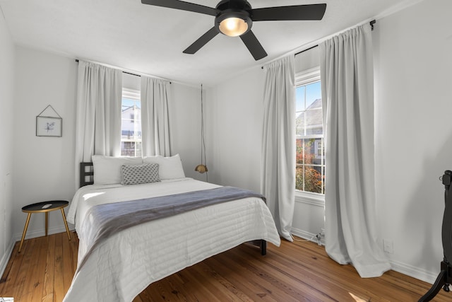 bedroom with hardwood / wood-style flooring, ceiling fan, and multiple windows