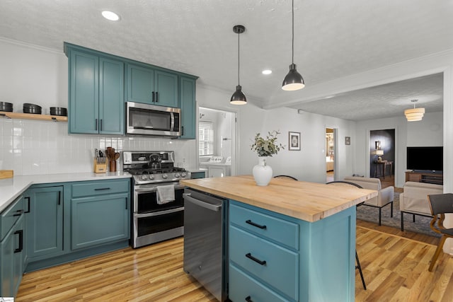 kitchen featuring wooden counters, independent washer and dryer, backsplash, pendant lighting, and appliances with stainless steel finishes