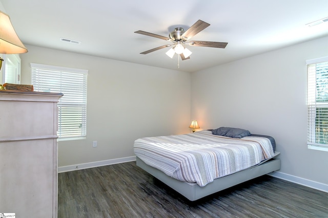 bedroom with ceiling fan, dark hardwood / wood-style floors, and multiple windows