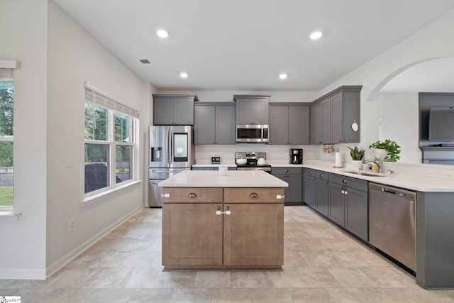 kitchen with gray cabinets, sink, stainless steel appliances, and a kitchen island