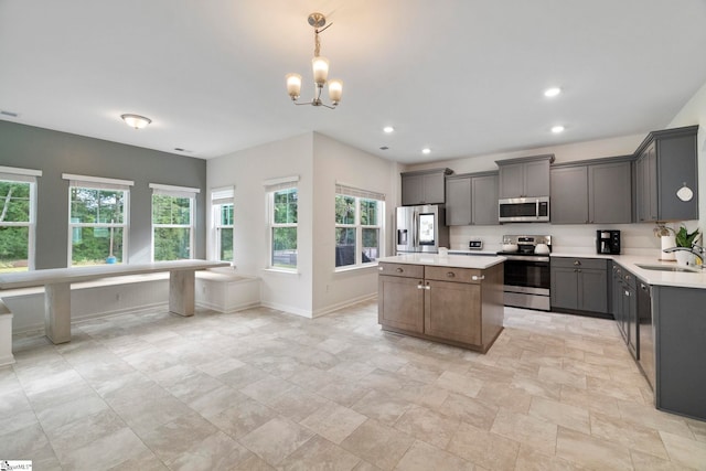 kitchen featuring gray cabinetry, stainless steel appliances, sink, pendant lighting, and a center island