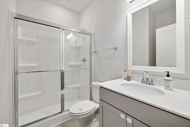 bathroom featuring tile patterned flooring, vanity, a shower with shower door, and toilet