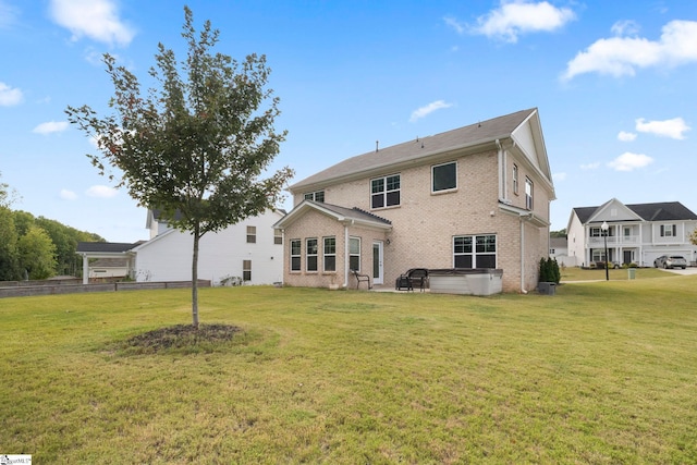 back of property featuring a yard and a hot tub