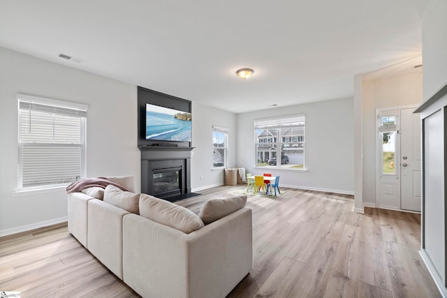 living room featuring a large fireplace, light hardwood / wood-style flooring, and a wealth of natural light