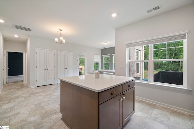 kitchen with decorative light fixtures, a kitchen island, and a chandelier