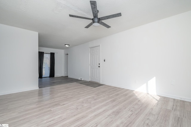 spare room with ceiling fan, a textured ceiling, and light wood-type flooring