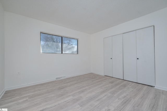 unfurnished bedroom with light hardwood / wood-style floors and a closet