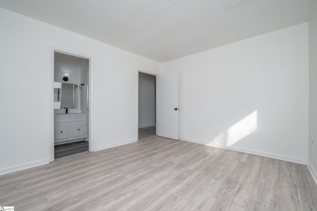 unfurnished bedroom featuring light hardwood / wood-style flooring and ensuite bath