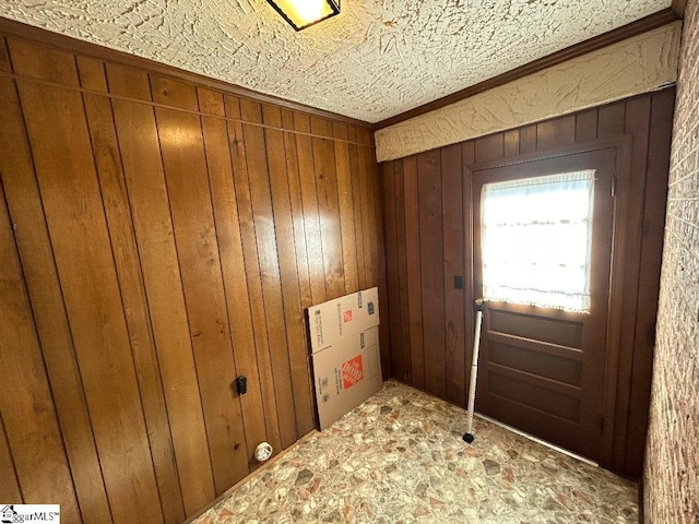 doorway to outside featuring a textured ceiling and wooden walls