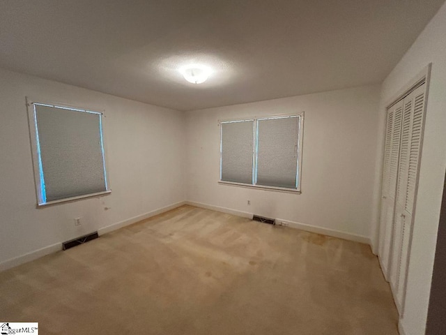 unfurnished bedroom featuring a closet and light colored carpet