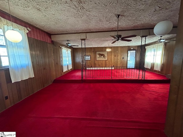 interior space featuring ceiling fan, wood walls, a textured ceiling, and a baseboard heating unit