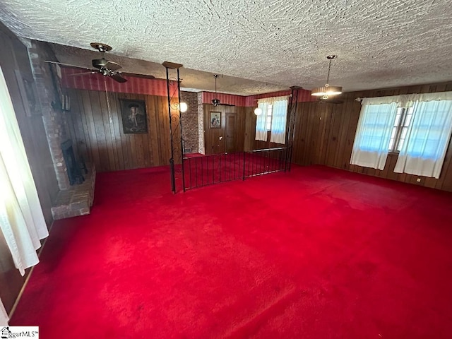 basement with a textured ceiling, ceiling fan, a healthy amount of sunlight, and wood walls