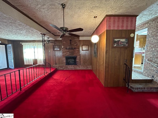 unfurnished living room featuring a fireplace, a textured ceiling, ceiling fan, and wooden walls