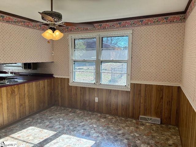 kitchen featuring ceiling fan and wooden walls