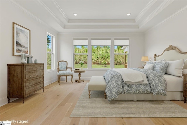 bedroom with light hardwood / wood-style floors, crown molding, and a tray ceiling