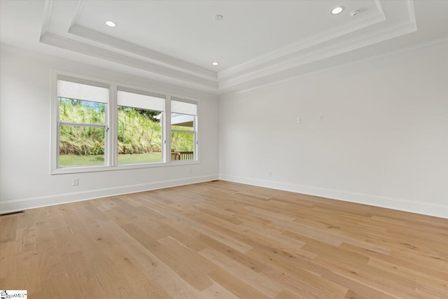 spare room with a tray ceiling, light hardwood / wood-style flooring, and ornamental molding