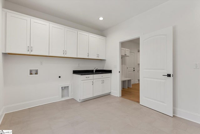 clothes washing area with hookup for an electric dryer, hookup for a washing machine, cabinets, and sink