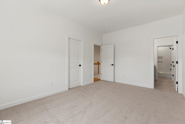 unfurnished bedroom with light colored carpet and ensuite bath