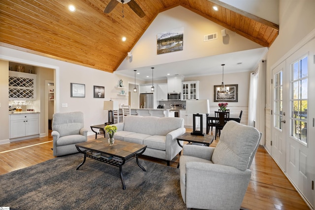 living room featuring light hardwood / wood-style flooring, wooden ceiling, high vaulted ceiling, bar, and ceiling fan with notable chandelier