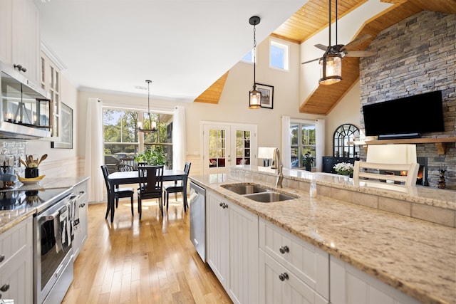 kitchen featuring stainless steel appliances, sink, light stone counters, white cabinets, and pendant lighting