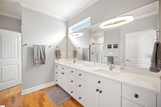 bathroom with ornamental molding, vanity, hardwood / wood-style floors, and a shower with shower door