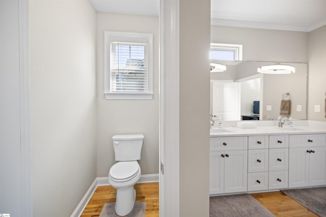 bathroom featuring toilet, hardwood / wood-style flooring, vanity, and ornamental molding